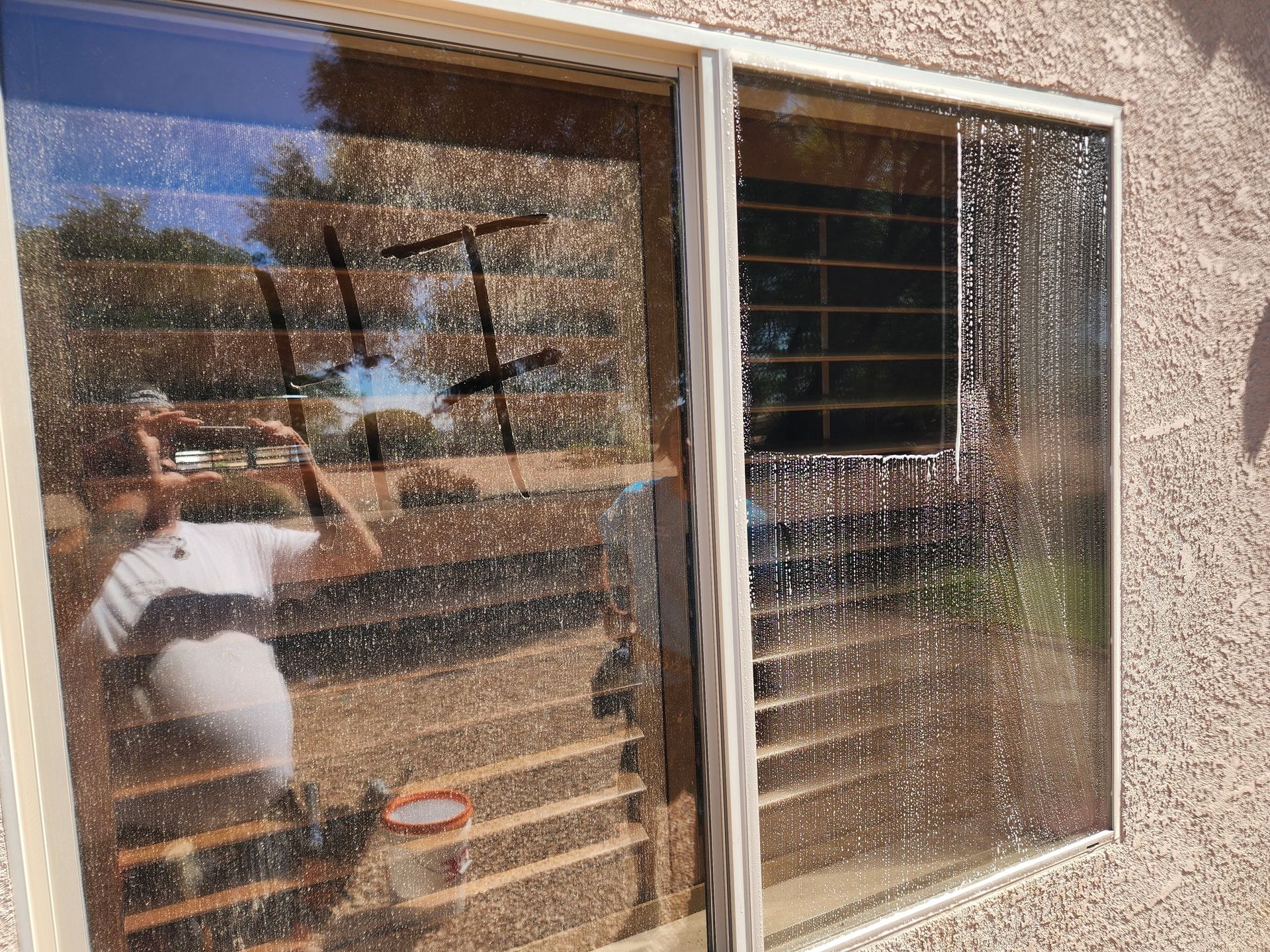 Mr Bailey drawing "HI" on a dirty window before cleaning with a quarter cleaned window on the otherside
